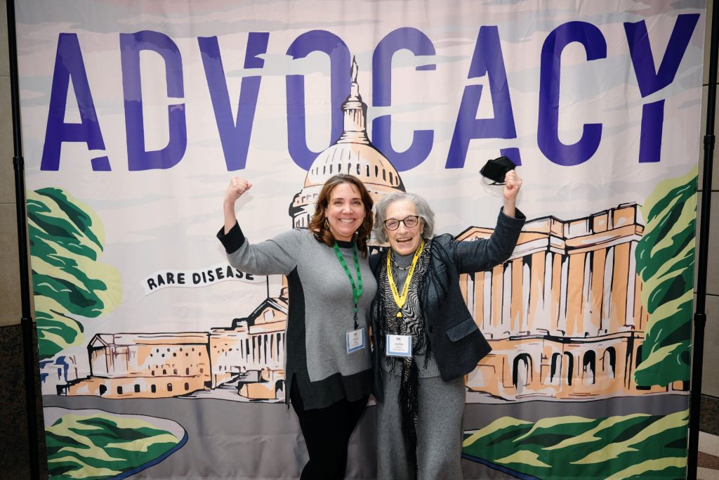 Two advocates make strong arms in front of advocacy banner