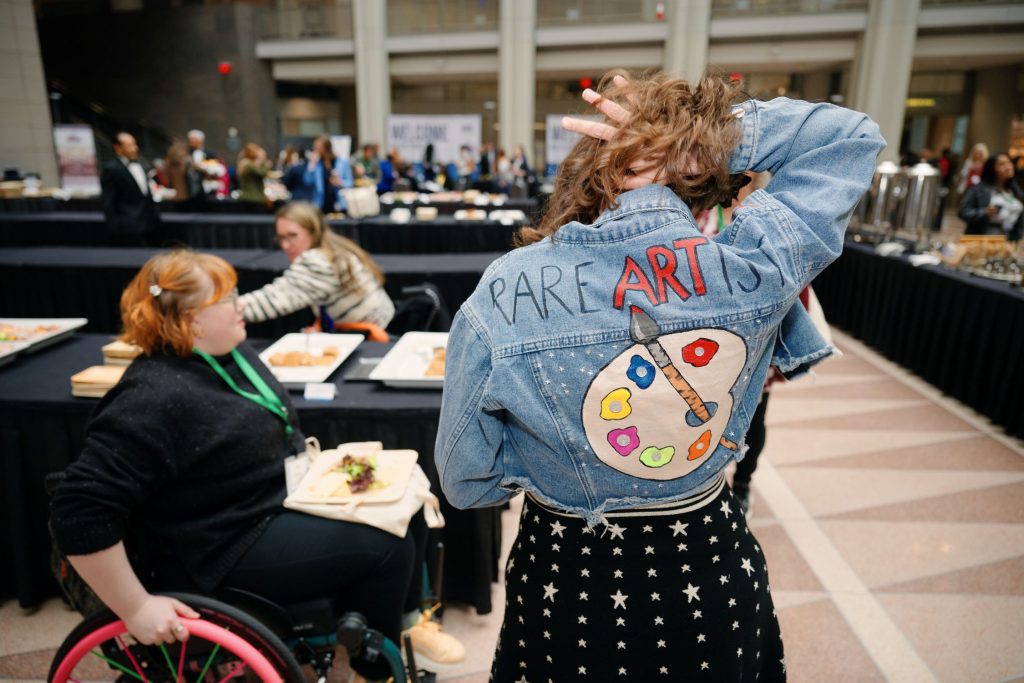Artist shows back of painted jacket at RARE Foundation event